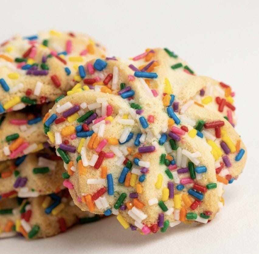 Delicately handcrafted Italian butter spritz cookies with a rich, buttery crumb and tender melt-in-your-mouth texture. Each cookie is finished with a vibrant coating of colorful sprinkles for a festive touch that balances nostalgic charm with gourmet refinement
